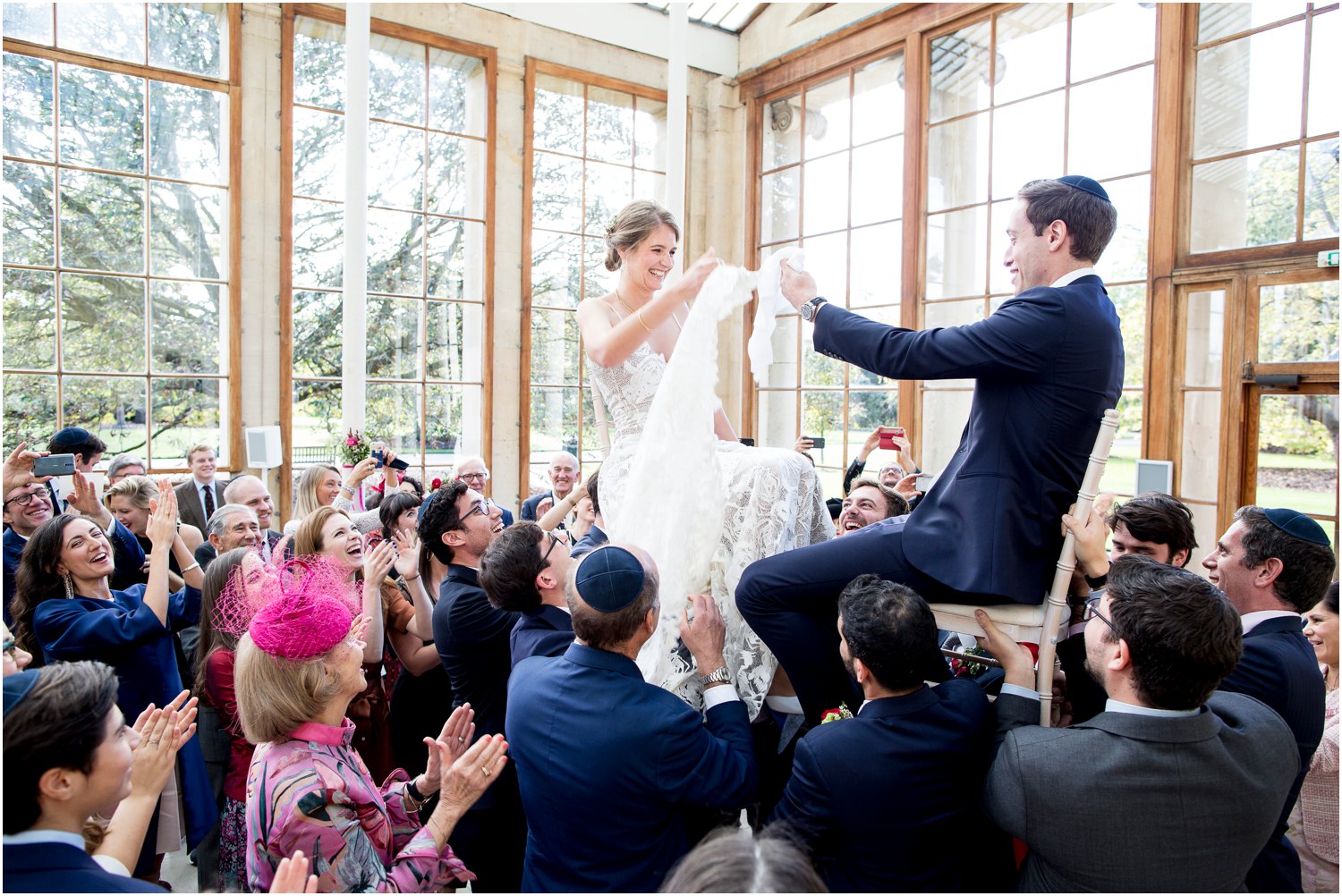 bride and groom on chairs at Jewish wedding at Nash Conservatory in Kew Gardens